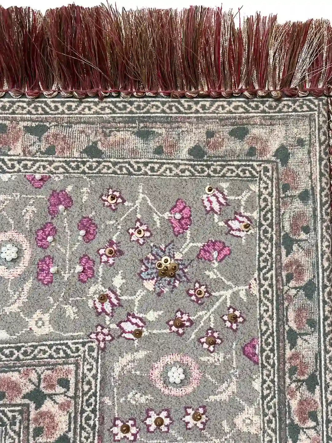Macro view of the ornate border showing gold sequins, white pearls, and the premium silk fringe texture